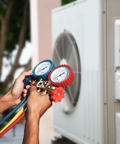 Technician holding manifold gauge measuring tool on fan for checking pump